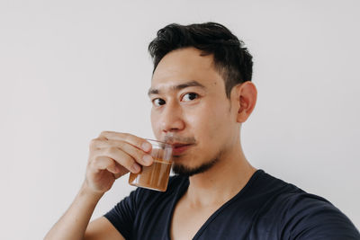 Young woman drinking water against white background