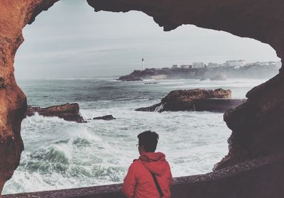 Rear view of woman looking at view of sea standing by retaining wall