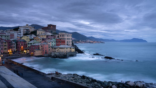 Buildings by sea against sky at dusk