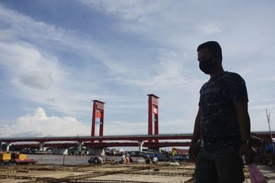 Rear view of man standing at airport against sky