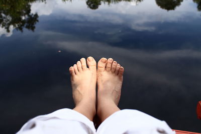 Low section of person legs on water against sky
