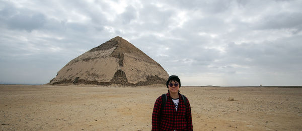 Portrait of man standing on desert against sky