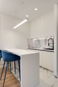 Bright kitchen with white island and blue chairs in a modern style