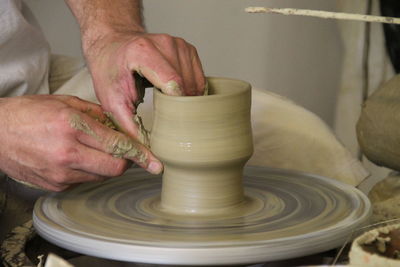 Midsection of potter molding clay in workshop