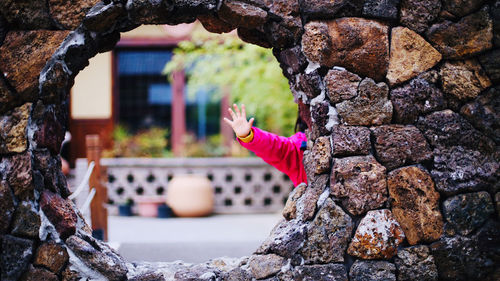 Side view of woman on rock against brick wall