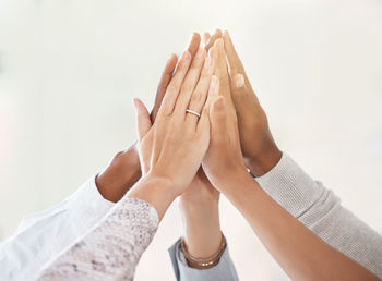 Low section of couple holding hands against white background