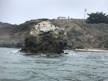 Rock formation in sea against clear sky