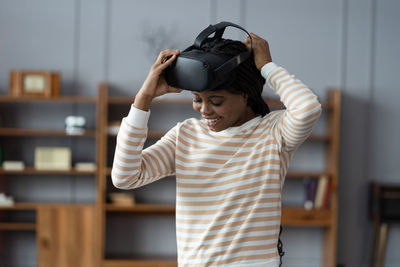 Inspired afro woman at home put on vr helmet to enjoy virtual reality online game cyber simulation