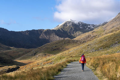 Rear view of woman walking on mountain against sky