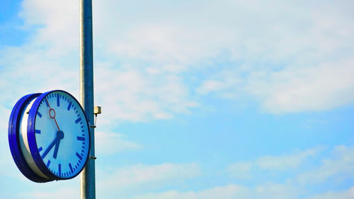 Low angle view of clock against blue sky