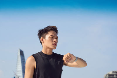 Low angle view of young man looking away against sky