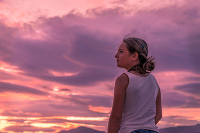 Low angle view of woman looking away against sky during sunset