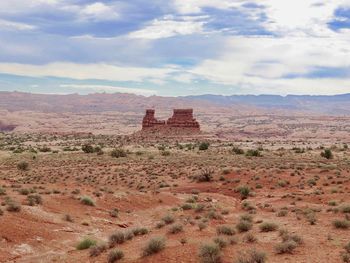 Scenic view of desert against cloudy sky