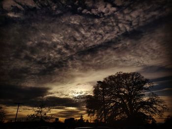 Low angle view of silhouette trees against dramatic sky