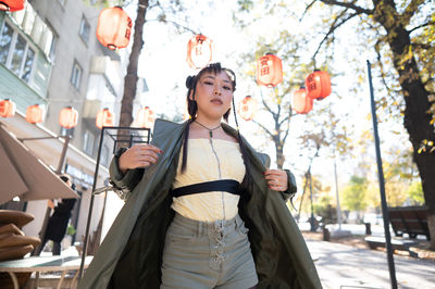 Portrait of young woman standing against building