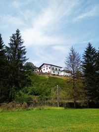 Trees and houses on field against sky