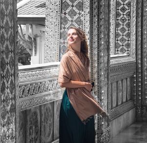 Portrait of a smiling young woman standing against wall