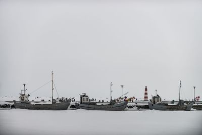 Boats moored at harbor against clear sky