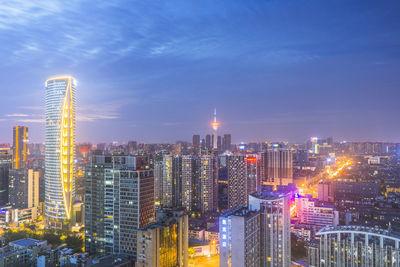 Illuminated buildings in city against sky