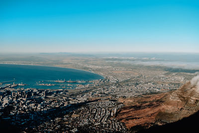 High angle view of sea and cityscape against clear blue sky