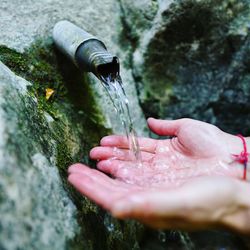 Close-up of hands holding water by fountain