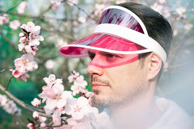 Close-up portrait of young man with pink flowers