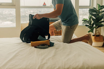 Midsection of woman sitting on bed at home