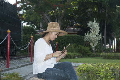 Woman using digital tablet while sitting at park