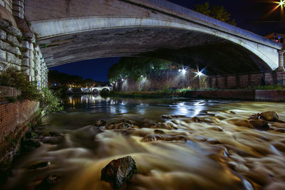 Illuminated bridge over river against sky at night