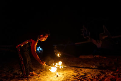 Side view of man with fire crackers at night