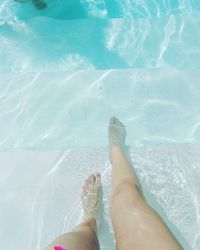 Low section of woman standing in swimming pool