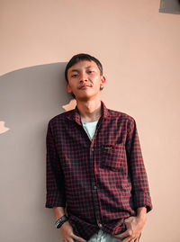 Portrait of young man standing against wall