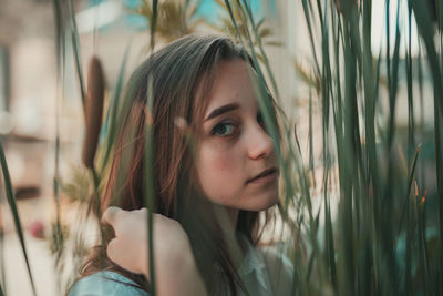 Close-up portrait of young woman standing by plants