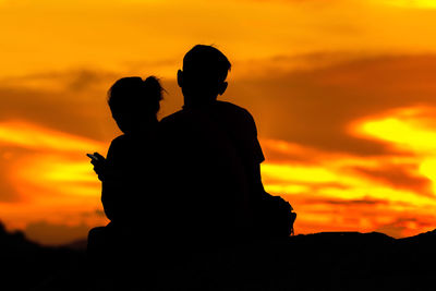 Silhouette couple against orange sky during sunset