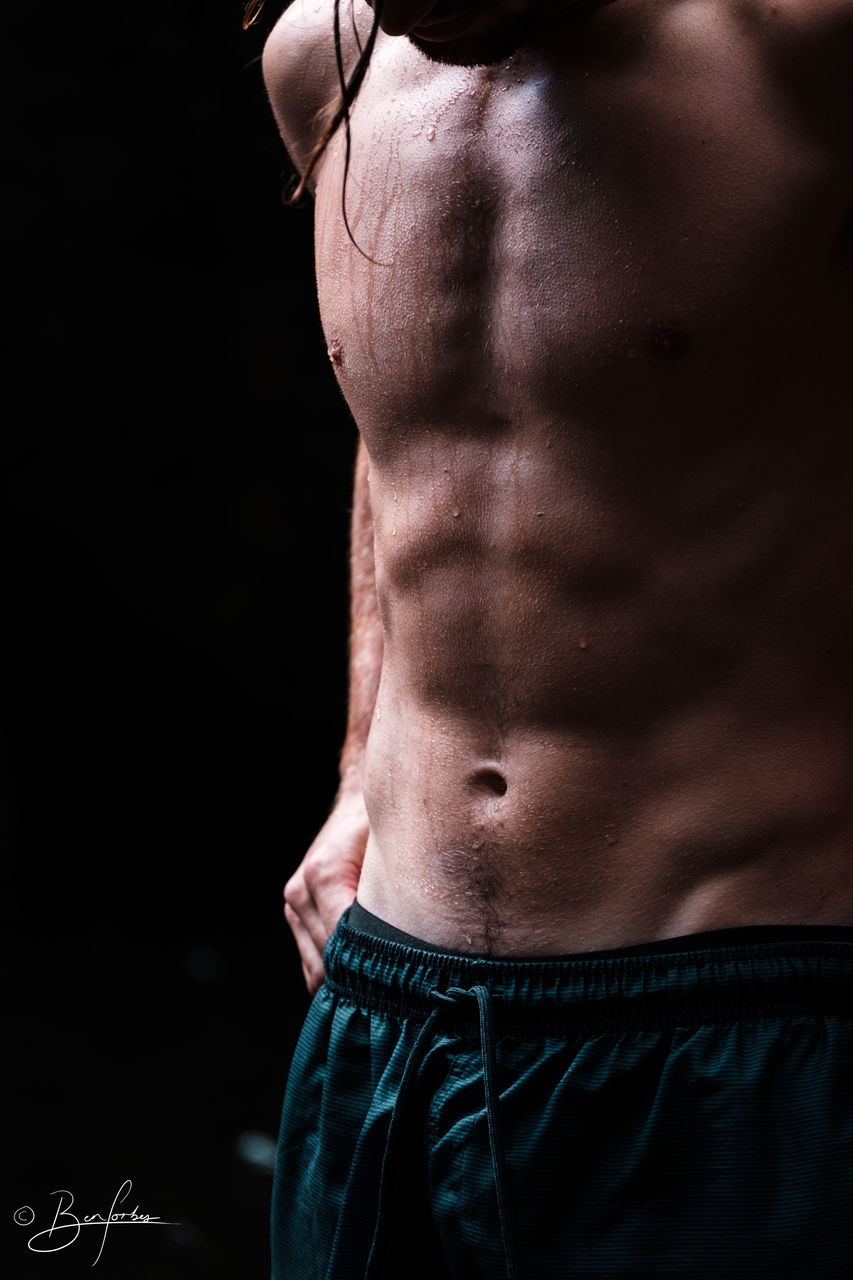 FULL LENGTH OF SHIRTLESS MAN WITH BLACK BACKGROUND