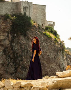 Portrait of woman standing against stone wall