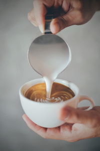 Cropped image of person pouring coffee in cup