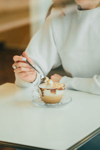 Midsection of woman holding ice cream on table