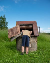 Full length rear view of child looking down to the well