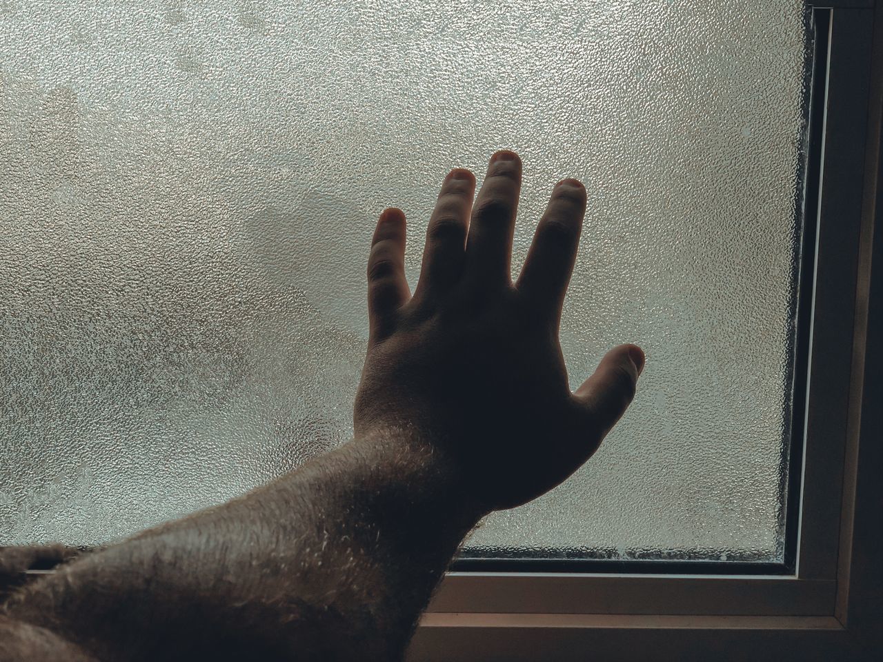 CLOSE-UP OF HAND TOUCHING WINDOW GLASS