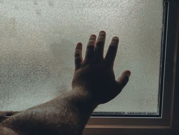 Close-up of hand touching glass window