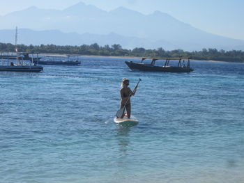 Man fishing in sea against sky