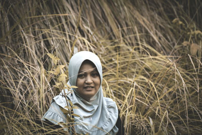 Portrait of smiling woman standing amidst plant