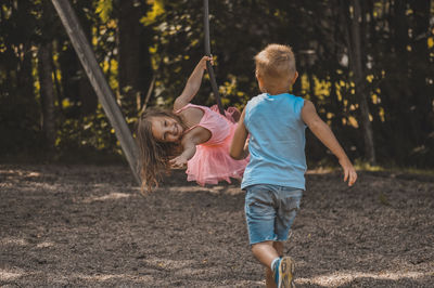 Rear view of girl and boy enjoying on playground 