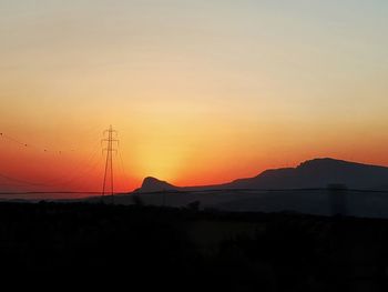 Silhouette mountains against orange sky