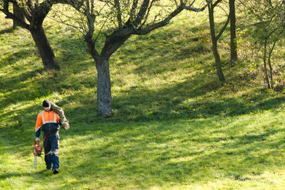 Full length of man carrying log walking on grassy field