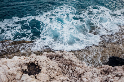 High angle view of sea waves splashing on rocks