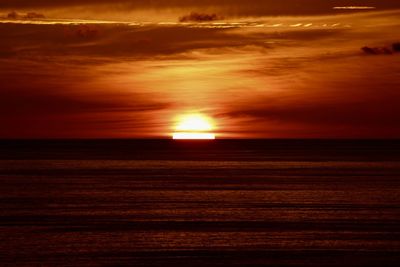 Scenic view of sea against dramatic sky during sunset