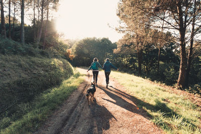 Rear view of couple running on dirt road with dog