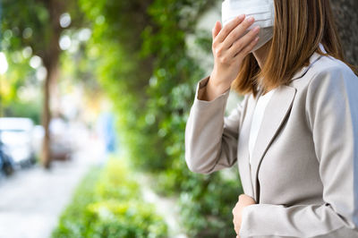 Midsection of woman wearing hat against trees